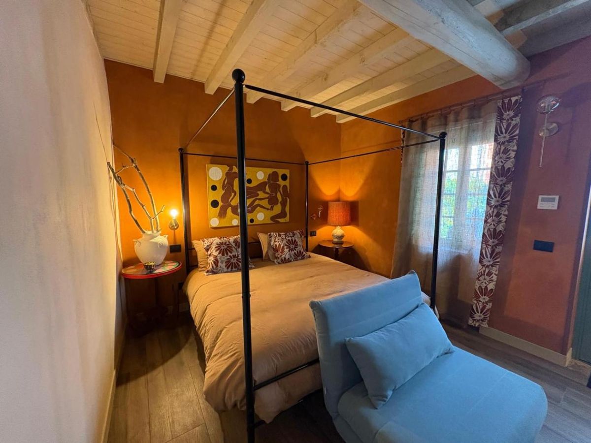 Junior Suite con letto a baldacchino in ferro battuto e pareti color ocra